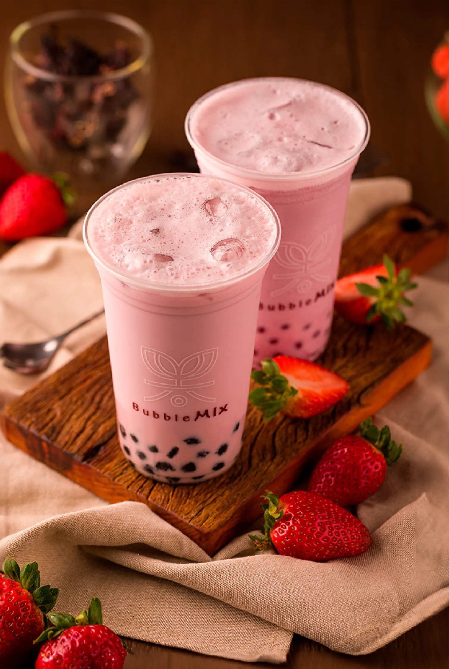 Dois copos de bubble tea de morango da Bubble Mix sobre uma tábua de madeira